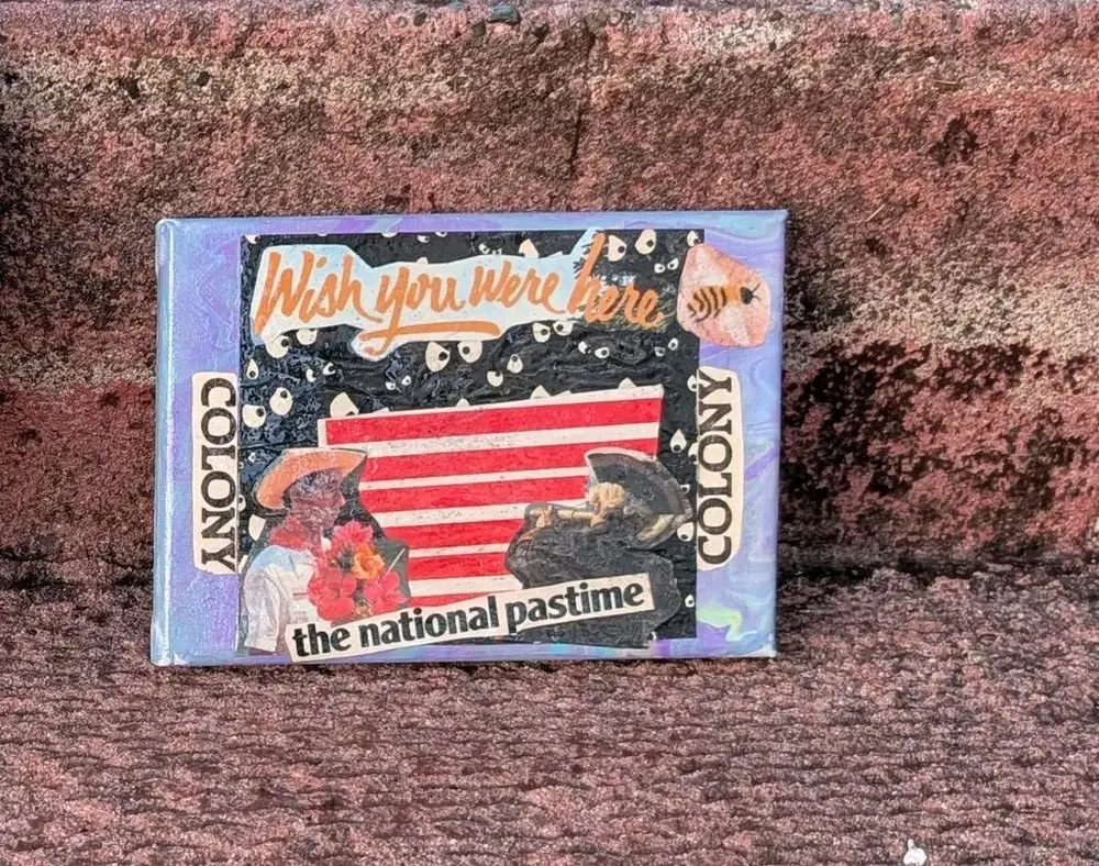Small collage on a lilac and blue marbled ground. A black panel scattered with cartoon eyes holds the words Wish you were here in orange script, red and white stripes, two cut-out figures in straw hats, and a strip reading the national pastime. The word COLONY runs down both sides, and a bee sits in the top corner.