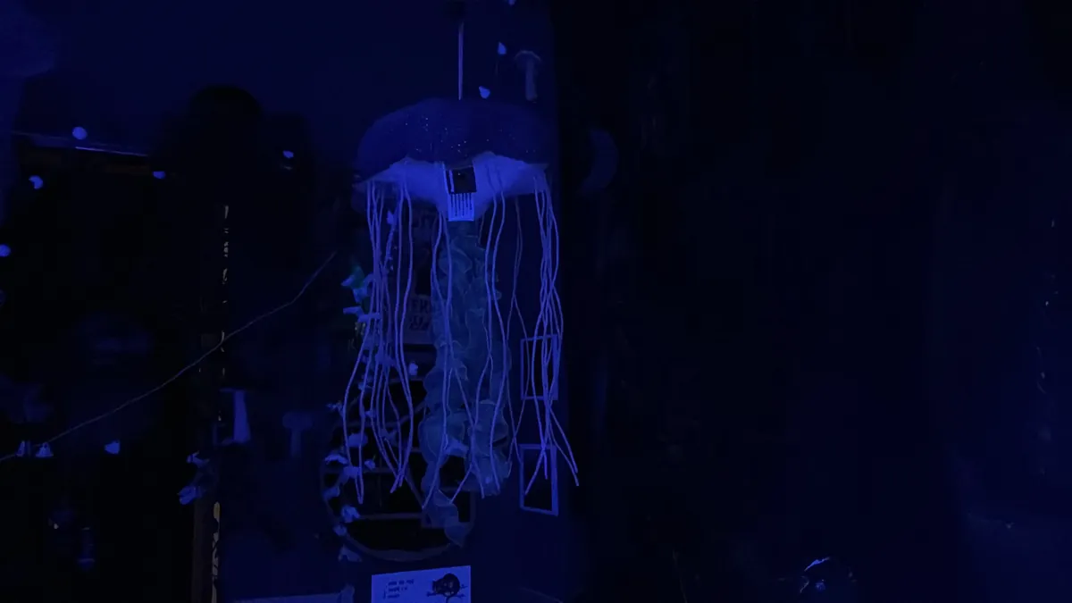 A jellyfish lamp with long trailing tendrils glows in a dark blue room.