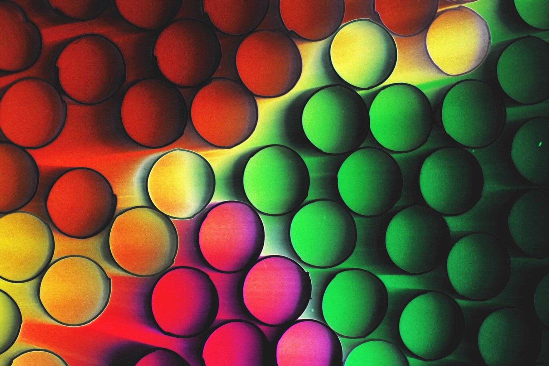 The ends of a box of fluorescent drinking straws, packed tight, glowing red, yellow and green.